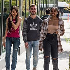 Three students walking on a path outside on campus