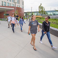 Several students walking on the pathway outside of University Hall