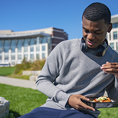 student eating food on front lawn in front of campus center